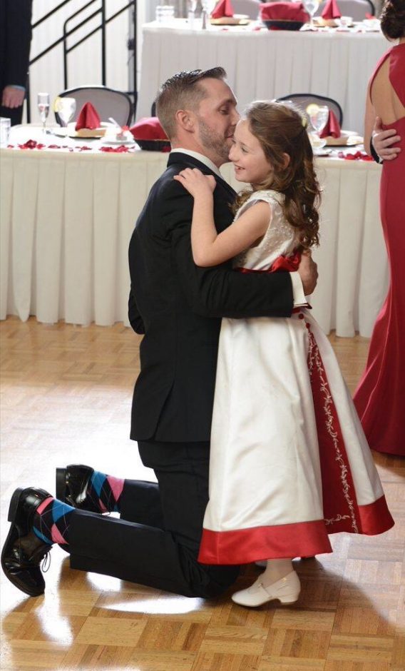 flower girl in red and white dress dancing with the groom