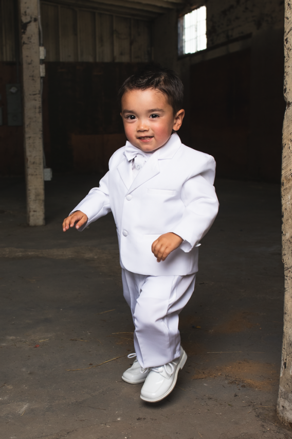 Boys 5-piece white tuxedo for infants to teenagers. Black, Ivory, or White Tuxedo includes a jacket, pants, vest, shirt, and a bow tie.