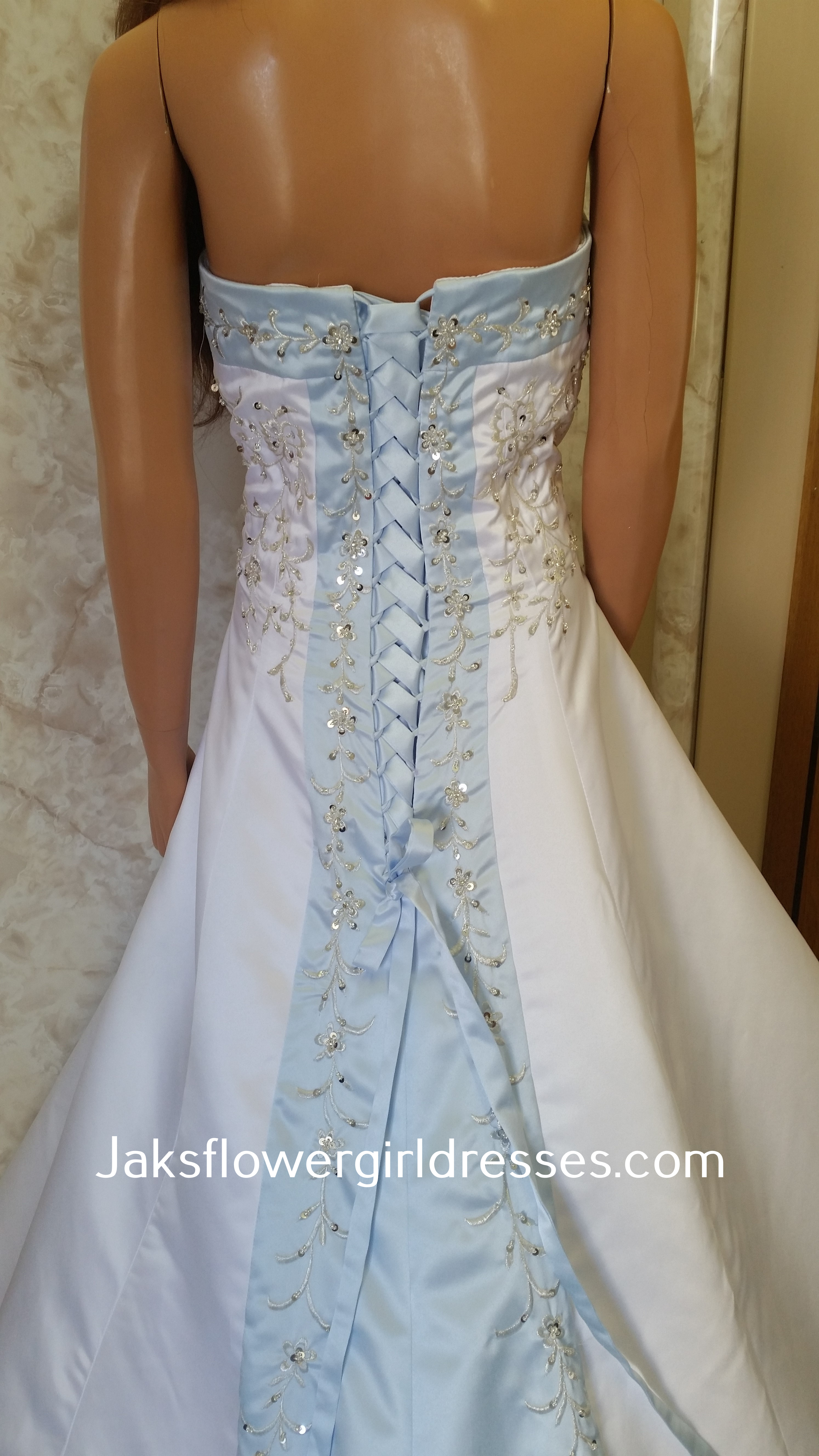 White dress for wedding flower girls. Light blue trimmed neckline, lace up back and chapel train with beaded embroidery.