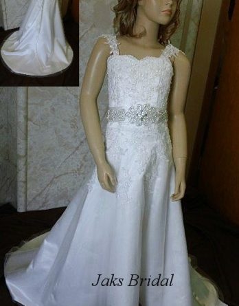 Lace flower girl dress with bridal sash and a floor length skirt with a train.