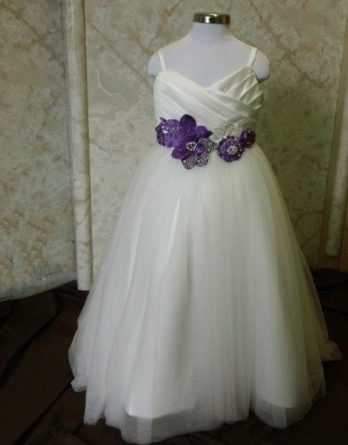 Purple and white flower girl dresses with a floral accent on the waist.