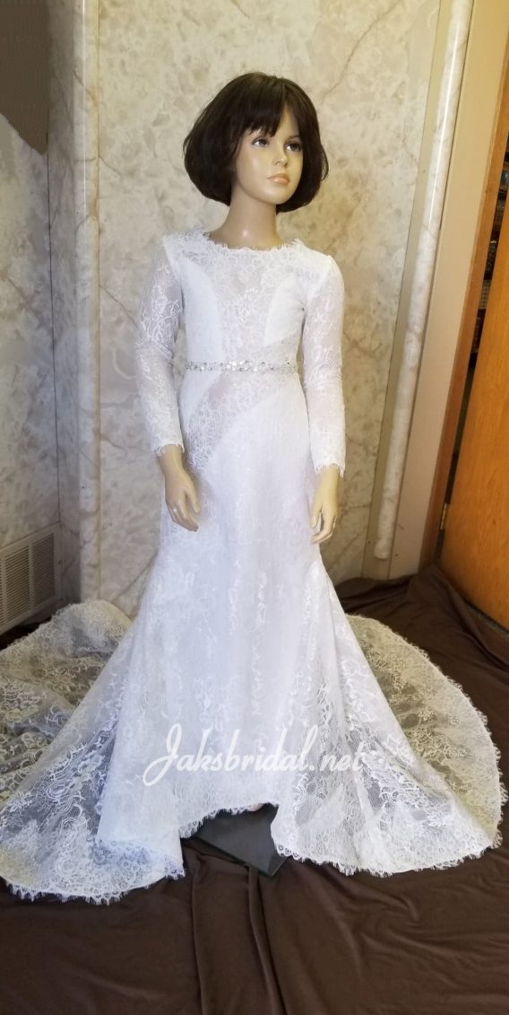 Light ivory lace dress with an illusion bateau neckline, beaded waist, and tastefully inserted illusion panels make this a high fashion flower girl dress. Completed with lace illusion long sleeves and train.