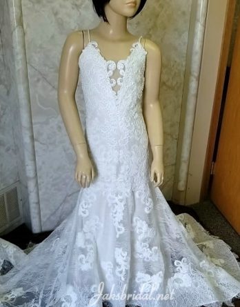 Embroidered lace flower girl dress with beaded spaghetti straps. Covered buttons extend to the hemline of the sheer lace train.