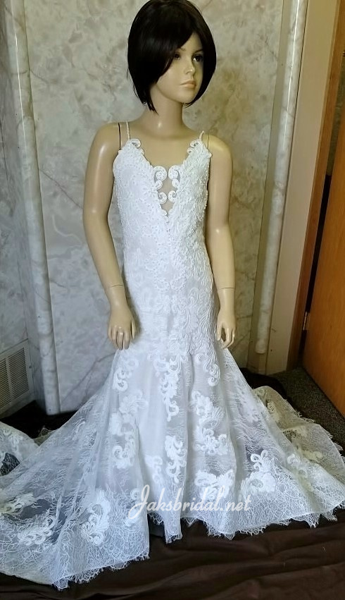 Embroidered lace flower girl dress with beaded spaghetti straps. Covered buttons extend to the hemline of the sheer lace train.