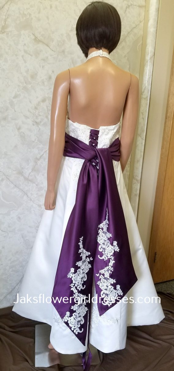 Halter wedding dress with hand-pattern lace, waistline accented with contrasting band and back streamers, completed with a high low skirt with front split.